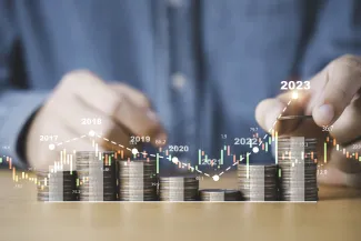 Homem manipulando moedas formando um gráfico com as mesmas.